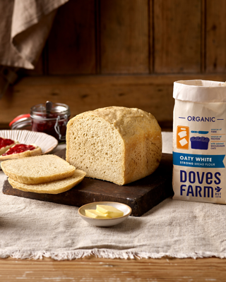 A rustic scene featuring freshly baked homemade bread made with organic oaty white flour. The mood is warm and inviting.