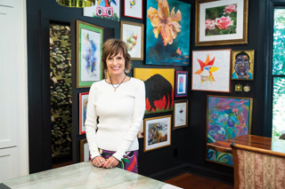 Allie Balling stands in front of a backdrop of original, colorful artwork in her kitchen and dining area.