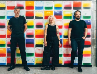 BOOM Club’s Sean Thegen, Rachelle Sickerott and Nick Williams stand before an interactive wall of bright liquid tiles at the electronic music clubhouse.